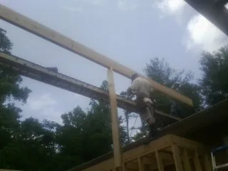 Carpenter setting a ridge beam over a new addition frame — Ice Dam Removal by Roofing Brothers in Chataignier