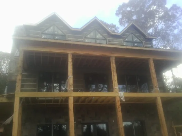 Dormers and porch framing on a large log home under construction — Roof Coating work by our crew in Chataignier