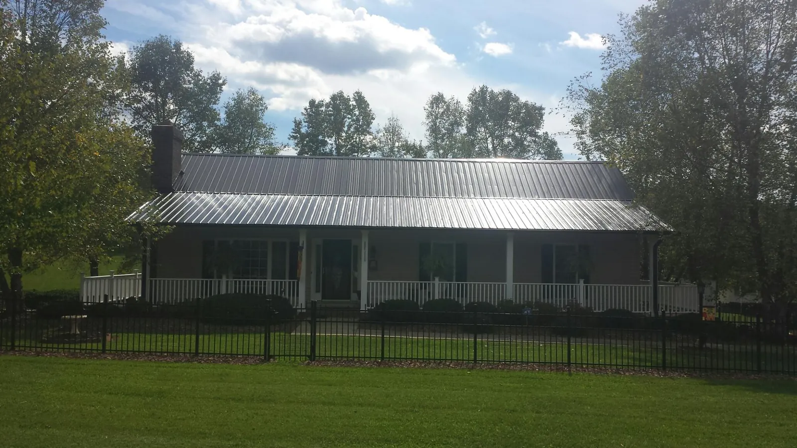 Gray metal roof on a brick ranch with a full width front porch — Gutter Guard Installation work by our crew in Chataignier