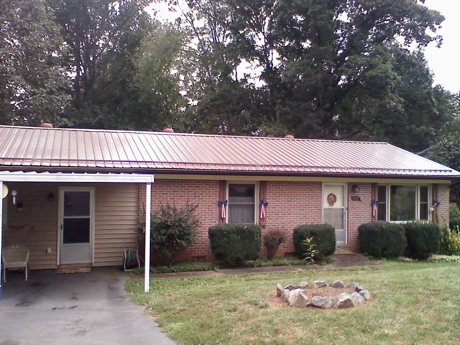 Bronze metal roof and carport on a brick ranch home — Roof Repair work by our crew in Chataignier