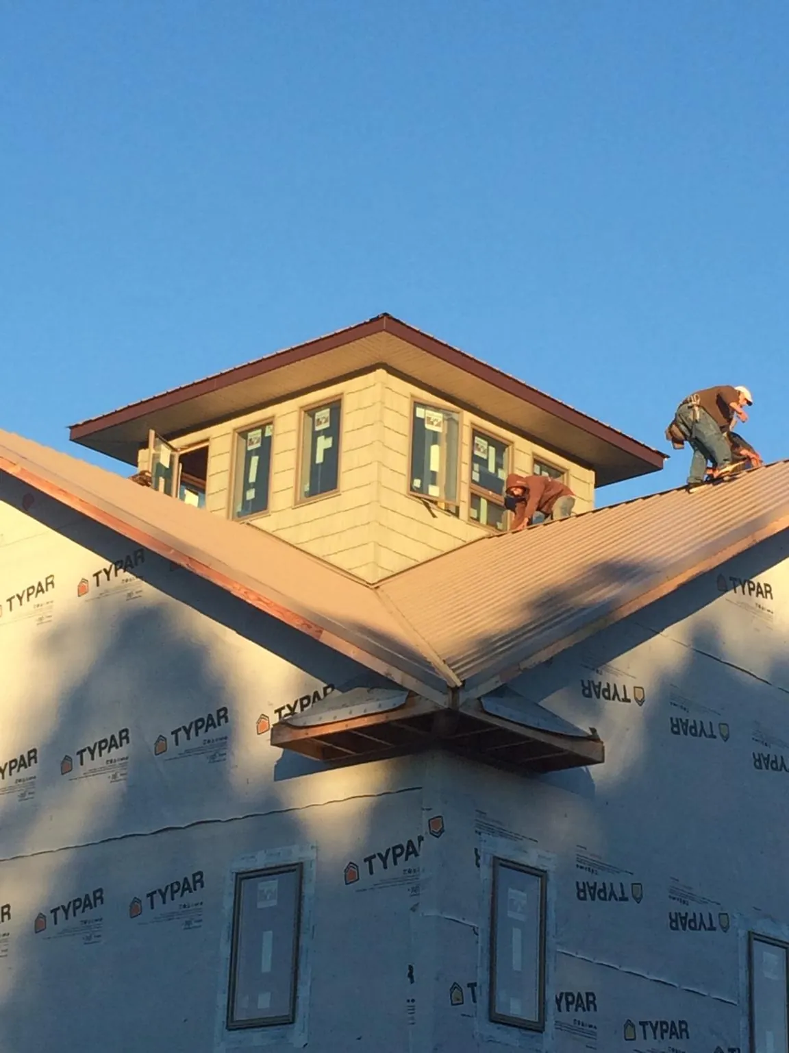 Roofers working around a rooftop cupola on a new metal roof at sunset — Roof Waterproofing in Chataignier by Roofing Brothers